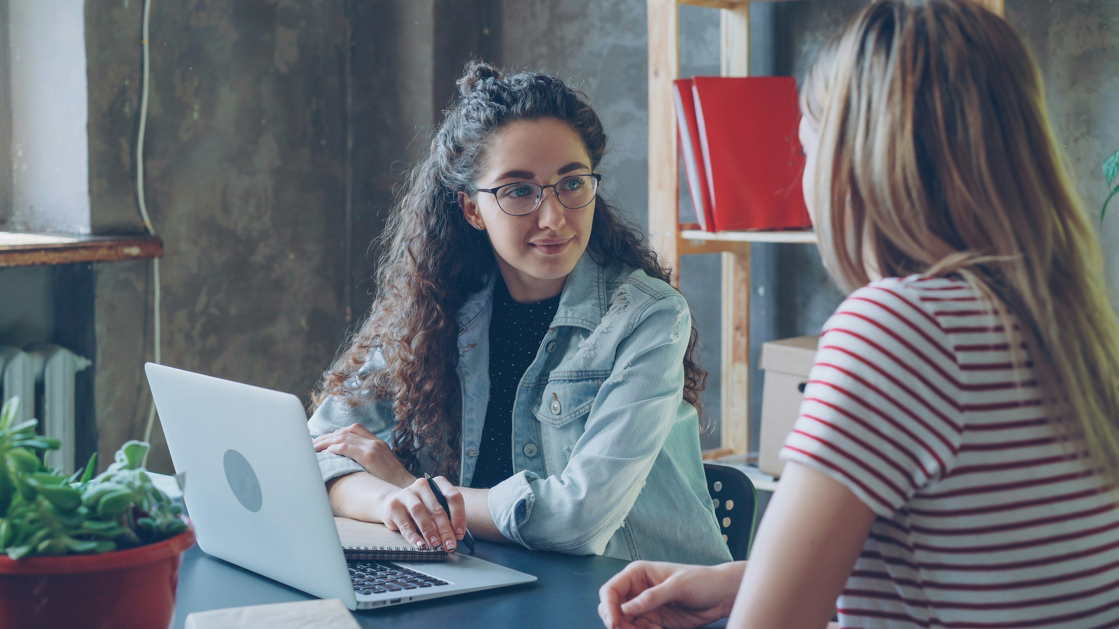 Une conseillère échange avec une personne accompagnée, assises côte à côte à un bureau.
