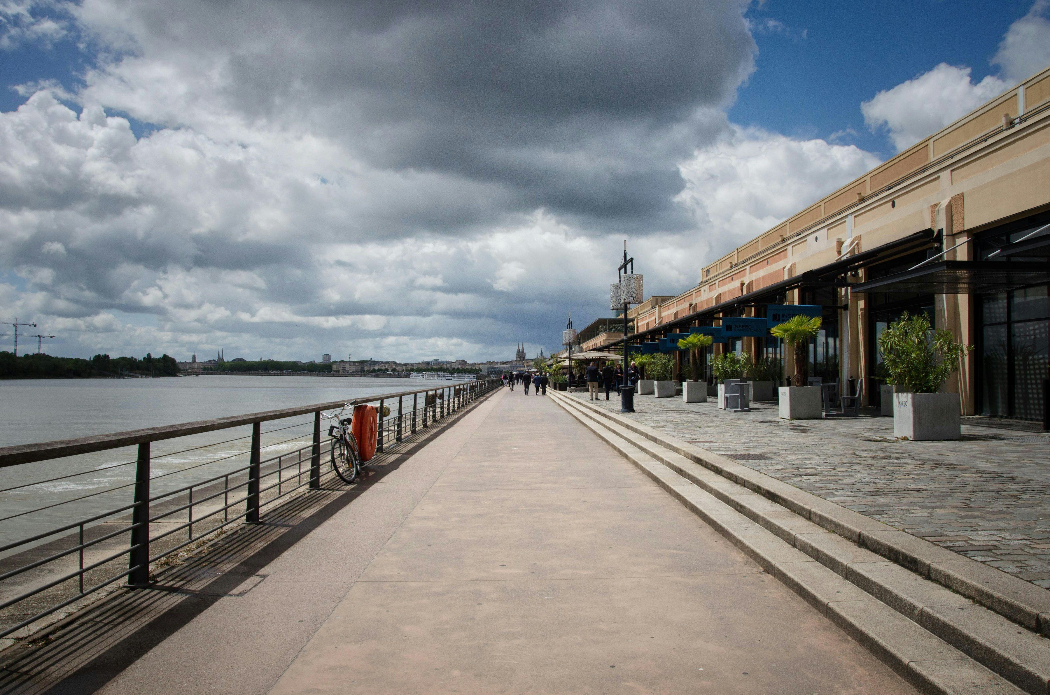 Les quais de Bordeaux au bord de la Garonne, sous un ciel nuageux.