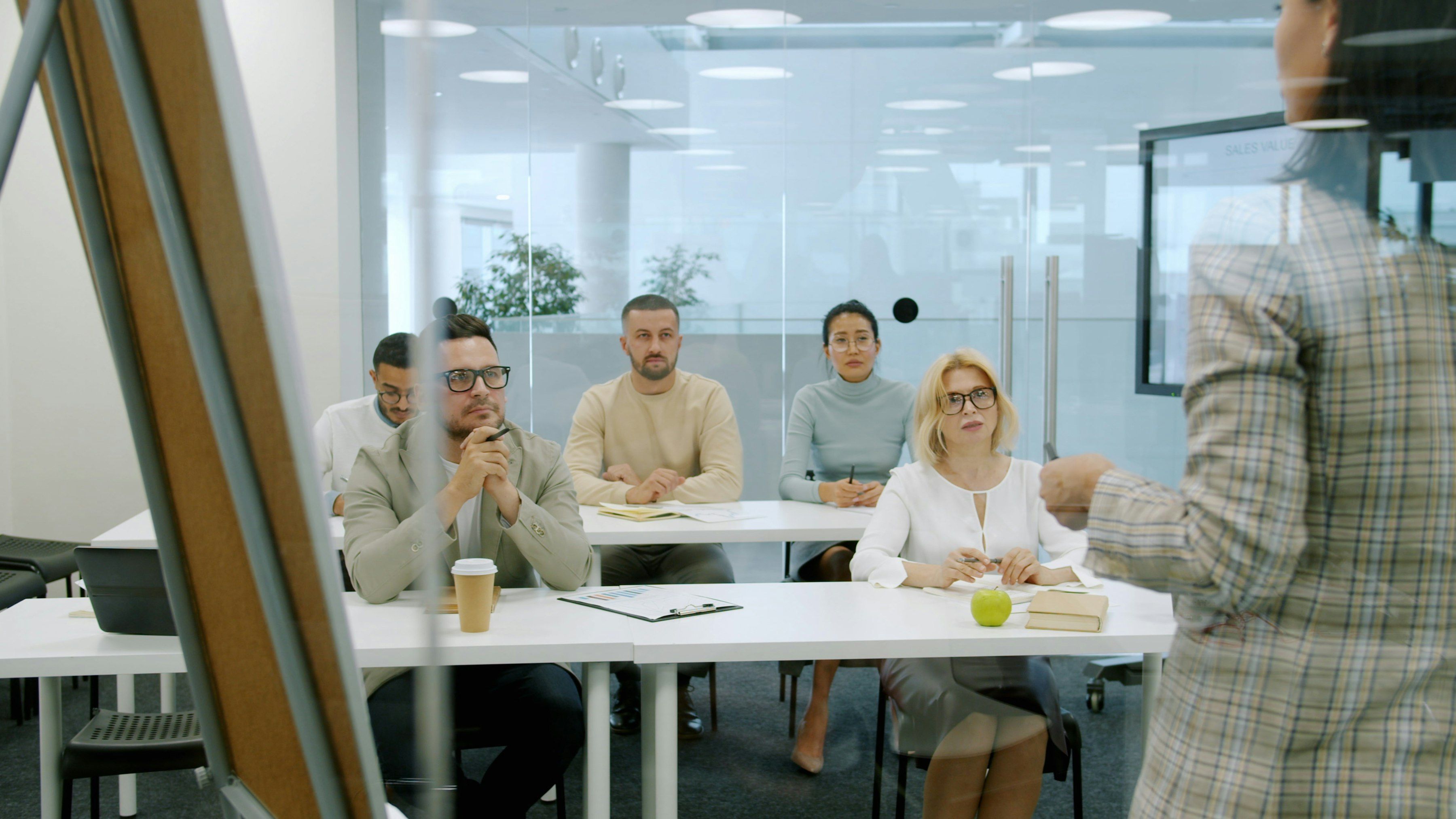 Une formatrice présente un support devant un groupe d’adultes assis en salle de formation.